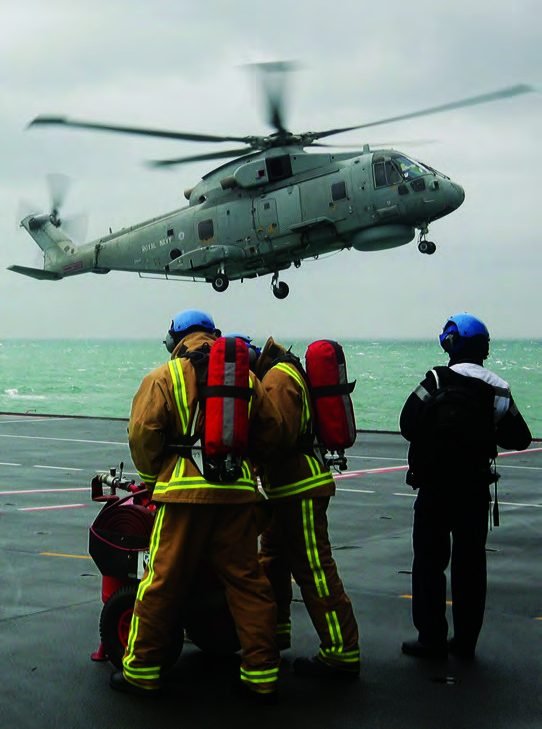 Flight deck crew on HMS Albion watch a Royal Navy Merlin helicopter